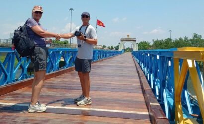 A scenic view of Hue's DMZ region under clear blue skies, featuring historic war sites, lush countryside, and a peaceful rural landscape. The image represents the best seasons and weather conditions for taking a Hue DMZ Tour.