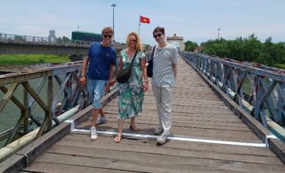 A comprehensive tour scene showing travelers exploring multiple Vietnam DMZ sites near Hue with a guide, including tunnels, bridges, and former battlefields across green countryside landscapes.