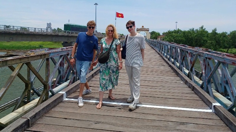 A comprehensive tour scene showing travelers exploring multiple Vietnam DMZ sites near Hue with a guide, including tunnels, bridges, and former battlefields across green countryside landscapes.